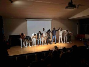 Sur une scène de spectacle, dix jeunes se tiennent la main et saluent l'assemblée.