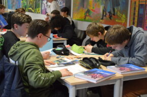 Quatre adolescents assis autour d'une table sont en train de dessiner.